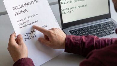 Una persona compara un documento de prueba en papel con las mismas líneas de texto en un portátil